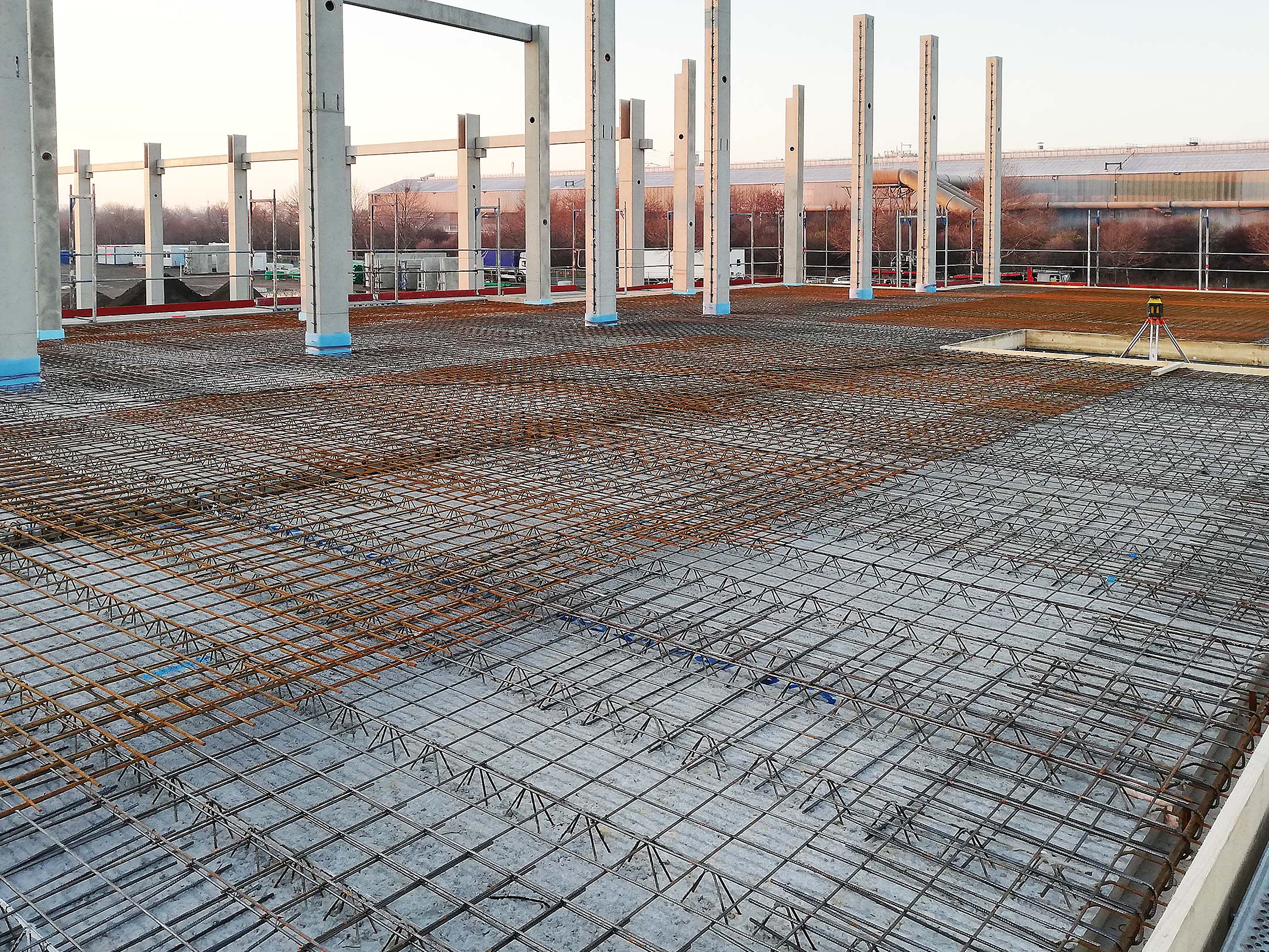 Zukunftstechnologie und Know-how Baugrund mit Betonstahlmatten und Stahlstützen bei Sonnenuntergang auf einer Baustelle.